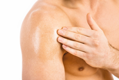 Muscular man applying testosterone gel on shoulder