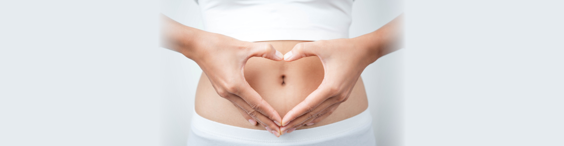 Close up of woman's hands made heart on belly